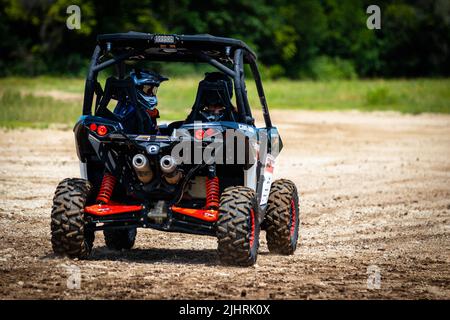 Un VTT avec des gens qui se conduisent et qui s'y conduisent sur un terrain sale et boueux au Rock Fest en 2020 Banque D'Images