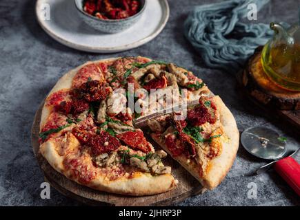 pizza végétalienne faite à la main avec tofu, tomates séchées et arugula en tranches Banque D'Images