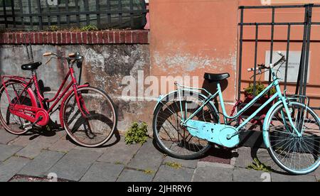 Les vélos rouillés rouge et bleu penchés sur les murs de bâtiment et la porte en métal Banque D'Images