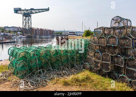 Pots de homard à la marina de James Watt, avec des yachts à quai et la grue de chantier naval en porte-à-faux au loin, Port Glasgow, Inverclyde, Écosse, Royaume-Uni Banque D'Images