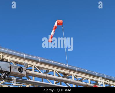 Photo basse d'une chaussette rouge et blanche sur un tube métallique contre un ciel bleu Banque D'Images