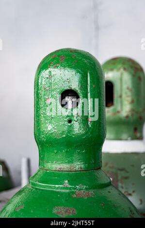 Bouteilles de gaz comprimé stockées verticalement fixées par une chaîne métallique et un bouchon en métal. Banque D'Images