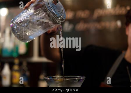 Gros plan des mains d'un barman en versant le martini dans un verre de champagne. Préparation d'un verre de champagne. Contexte barman préparation d Banque D'Images