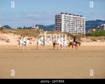 Un groupe d'amis à cheval sur la plage de Laredo dans le nord de l'Espagne Banque D'Images