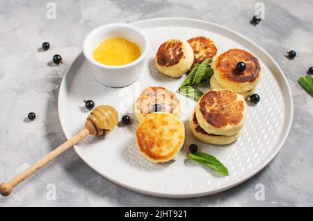 Crêpes au fromage cottage, beignets de ricotta ou syrniki au cassis. Petit déjeuner sain et délicieux. Banque D'Images