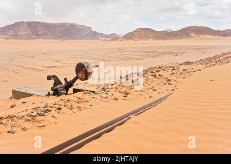 Ancien chemin de fer rouillé non utilisé à la gare de Wadi Rum, pistes couvertes de sable près, désert et montagnes en arrière-plan Banque D'Images