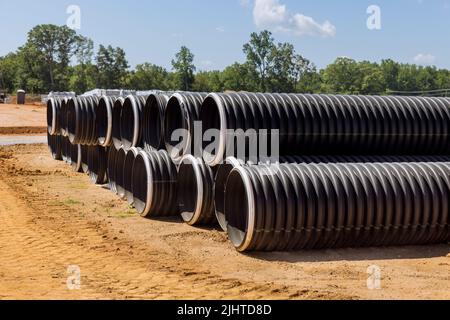 Nouveau tuyau en plastique noir avec un joint en PVC empilé en rangées sur le site de construction pour un système de vidange Banque D'Images