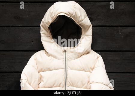 la veste d'hiver légère et bouffie pour femmes repose sur une table en bois noir, les vêtements d'hiver pour femmes se posent à plat Banque D'Images
