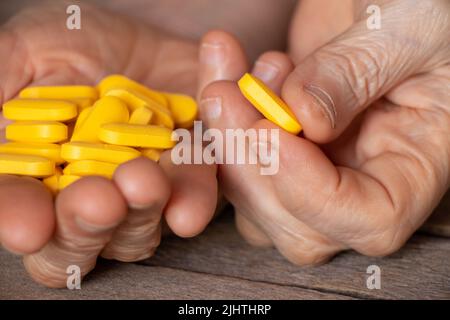 grand-mère tient des pilules jaunes dans ses mains sur une table en bois, des pilules dans les mains et des femmes couchée et des médicaments Banque D'Images