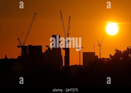 Tower Cranes silhouetted contre un lever de soleil dans le centre de Leeds City Center, West Yorkshire, Royaume-Uni Banque D'Images