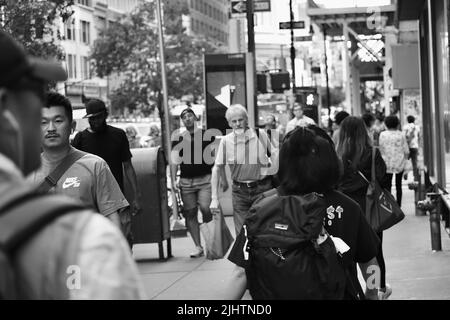 Une photo en niveaux de gris des personnes marchant sur le trottoir Banque D'Images