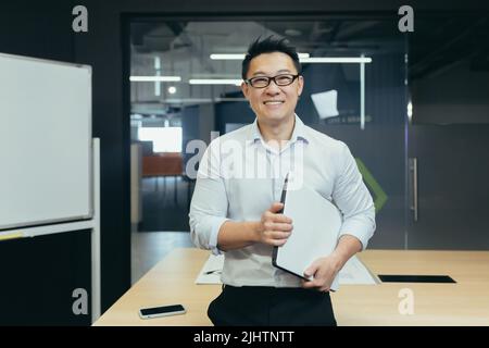 Portrait d'un professeur asiatique réussi dans un bureau universitaire moderne, homme souriant et regardant l'appareil photo Banque D'Images