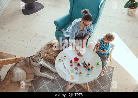 Maman et enfant peignent ensemble à la maison avec le chien Banque D'Images