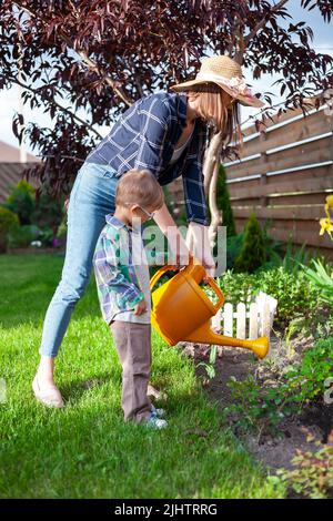 L'arrosage par les enfants et les mères peut arroser un jardin dans l'arrière-cour Banque D'Images