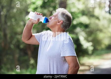Assurez-vous que vous obtenez une hydratation adéquate pendant vos entraînements. Un homme mature boire de l'eau tout en faisant de l'exercice à l'extérieur. Banque D'Images