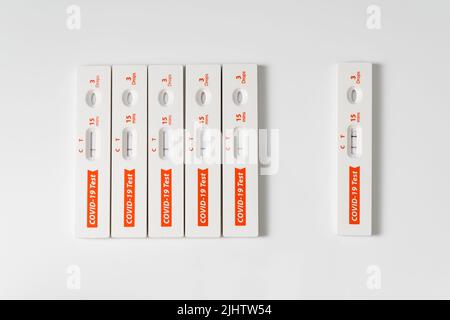 La rangée de kits de test rapide de l'antigène pour le covid-19 et un est positif. Banque D'Images