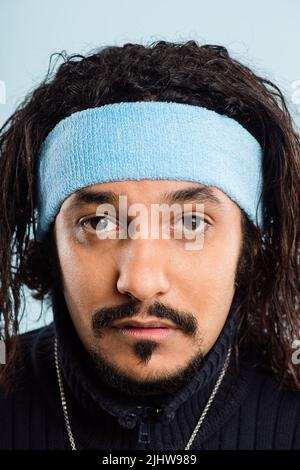 Je m'ennuie de cela. Un beau jeune homme debout seul dans le studio et posant tout en portant un bandeau. Banque D'Images