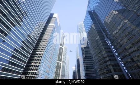 Photo en bas angle d'un avion volant au-dessus de gratte-ciel modernes dans le centre-ville Banque D'Images