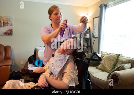 Athènes, Géorgie, États-Unis. 19th juillet 2022. Les professionnels du soutien direct qui aident et prennent soin des personnes handicapées vivant dans leur propre foyer sont de plus en plus rares, en grande partie en raison des bas salaires horaires dans la face de l'inflation. Les organisations à but non lucratif qui gèrent les soignants sont frustrées par des fonds limités provenant des budgets de dispense Medicaid de l'État, mettant des milliers de personnes dans la population nationale de personnes handicapées à risque, selon les défenseurs de l'invalidité. Photo : Mackenzie Bramblett, 27 ans, présente les cheveux de Callie Moore dans l'appartement de Callie. Callie, 27 ans, qui est médicalement fragile avec de multiples p Banque D'Images