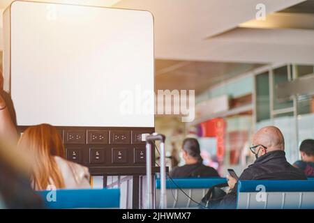 Homme expérimenté avec appareils de charge de smartphone dans le salon de l'aéroport avec chariot à bagages. Mise au point sélective, Travel concept. Banque D'Images