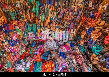 Hawker vendant des tongs colorées sur le marché de rue animé. Chaussures vibrantes, style décontracté, agitation des petites entreprises, ambiance estivale, vendeur en bord de route Banque D'Images