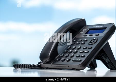 téléphone avec VOIP sur table blanche par fenêtre avec fond ciel flou. Service clientèle, concept de centre d'appels. Téléphone moderne VoIP. Communication Banque D'Images