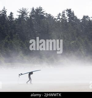 Jeune surfeur avec planche de surf dans la brume, plage Chesterman, Tofino, île de Vancouver, Colombie-Britannique, Canada. Banque D'Images