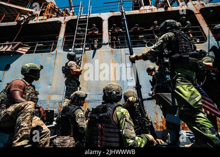 13 juillet 2022 - Baie de Souda, Grèce - Un équipage de combat de guerre spéciale navale américaine avec équipe de bateau spéciale ''“ DOUZE, groupe de guerre spéciale navale américaine QUATRE discute des procédures de crochet et de montée à l'aide d'une échelle de spéléologie sur un assaut de navire de combat avec des Marines suédoises avec 4th Marine Regiment, Corps amphibie suédois et Marines de reconnaissance des États-Unis avec la Direction de l'instruction spéciale, Groupe de formation des opérations expéditionnaires, I Force expéditionnaire maritime pendant l'exercice TYR 22 au Centre d'instruction opérationnelle d'interdiction maritime de l'OTAN (NSIOTI) à Souda Bay, Grèce, 13 juillet 2022. TYR 22 est un maritim Banque D'Images