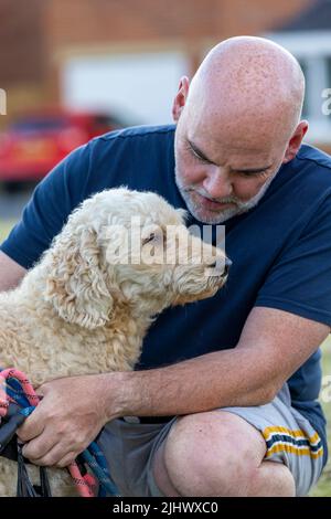 Moment affectueux entre un homme d'âge moyen et son beau chien de couleur beige Labradoodle Banque D'Images