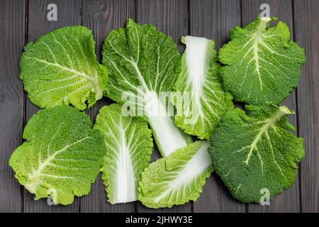 Feuilles de chou vert de Savoie frais. Pose à plat. Arrière-plan en bois sombre. Banque D'Images