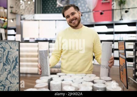 un homme dans un magasin de bois d'œuvre examine l'assortiment tout en regardant les racks avec des marchandises Banque D'Images