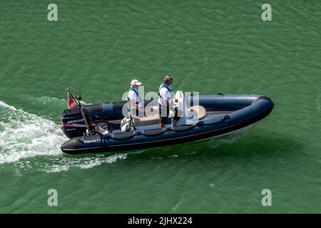 deux hommes dans un petit bateau gonflable rigide ou une côte avec un grand moteur hors-bord en cours sur une mer calme. Banque D'Images