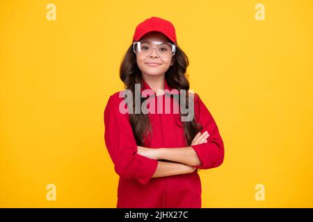 Visage heureux, émotions positives et souriantes de la jeune fille. Travailleur adolescent enfant portant une combinaison rouge, un capuchon et des lunettes de protection. Portrait en studio Banque D'Images