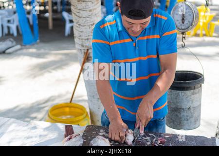 Pêcheur nettoyant poisson sur le marché local Banque D'Images