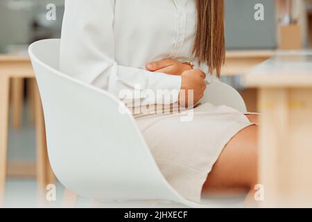 Gros plan d'une femme d'affaires de race mixte tenant le ventre douloureux tout en se sentant malade avec des crampes d'estomac menstruelles et des maux de ventre dans un bureau. Faim Banque D'Images