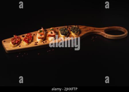 Une Bruschetta avec différentes garnitures servies sur un bureau décoratif en bois Banque D'Images