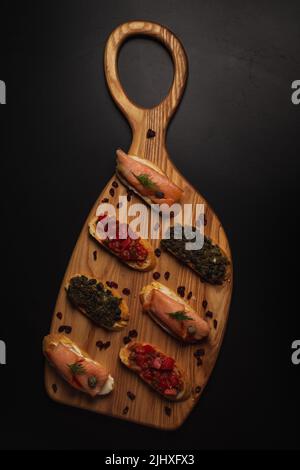 Un cliché vertical de Bruschetta avec différentes garnitures servi sur un bureau décoratif en bois Banque D'Images