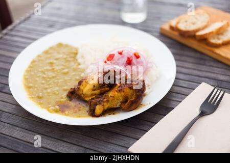 Plat péruvien. Ailes de poulet avec purée de pois, riz et oignons marinés Banque D'Images