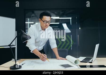 Un architecte asiatique prospère travaille en studio de conception, sur le plan de dessin du projet, fait des corrections Banque D'Images