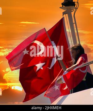 Istanbul, Turquie - juillet 2022 : une petite fille agitant le drapeau turc sur un navire. Jeune fille agitant le drapeau turc au coucher du soleil. Banque D'Images