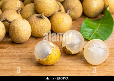 Vue rapprochée de la longan pelée et du tas de l'ensemble avec feuille verte sur une table en bois. Banque D'Images