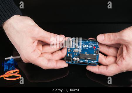 La carte Arduino UNO tient dans les mains Banque D'Images