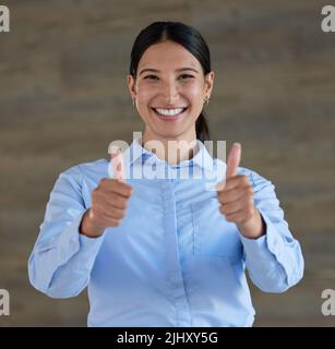 Portrait d'une course mixte gaie femme d'affaires souriante montrant le pouce vers le haut geste au travail. Jeune femme hispanique montrant un bon, gagnant, succès Banque D'Images