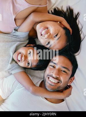 Bonne famille sur le lit. Portrait de famille heureuse d'en haut. Famille multiraciale au lit. Bonne fille se détendant avec ses parents Banque D'Images