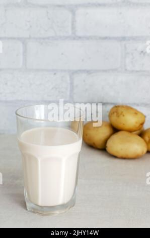 Un verre transparent avec du lait de pomme de terre sur la table. Une nouvelle tendance à manger sainement. Concept de nourriture alternative. Lait de légumes pour les végétaliens. Orientation verticale Banque D'Images