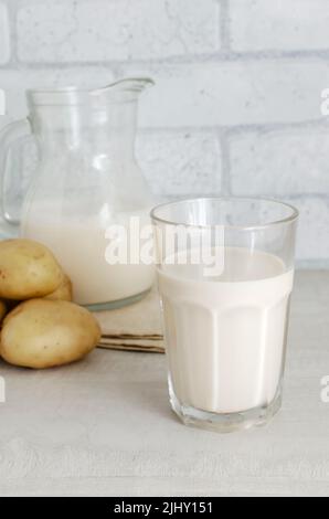 Un verre transparent et un pichet avec du lait de pomme de terre sur la table. Une nouvelle tendance à manger sainement. Concept de nourriture alternative. Lait de légumes pour les végétaliens. Verti Banque D'Images