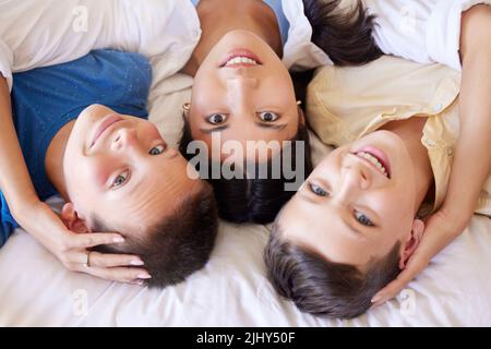 Portrait d'une famille de race mixte au lit. Mère avec ses fils adoptifs. Jeune mère se détendant avec ses enfants. Famille mixte de course de détente Banque D'Images