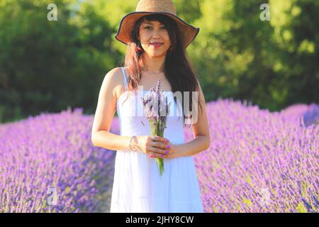 Belle femme en robe blanche tenant un bouquet de lavande à la main. Banque D'Images