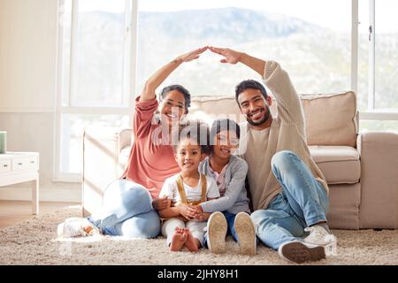 Couple souriant avec de petits enfants faisant un toit symbolique de mains sur leurs enfants. Sœurs mixtes protégées par les parents. Mère et père Banque D'Images