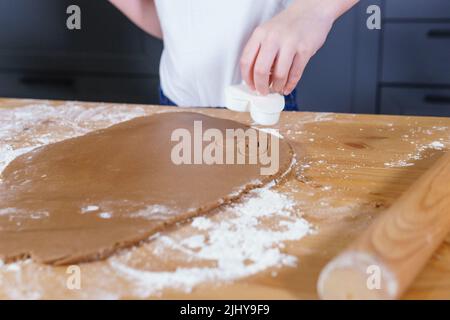 Une petite fille fabrique des biscuits en forme de cœur à partir de pâte de seigle. Le concept de la Saint-Valentin et de la cuisson saine. Cuisson des biscuits en gros plan. Banque D'Images